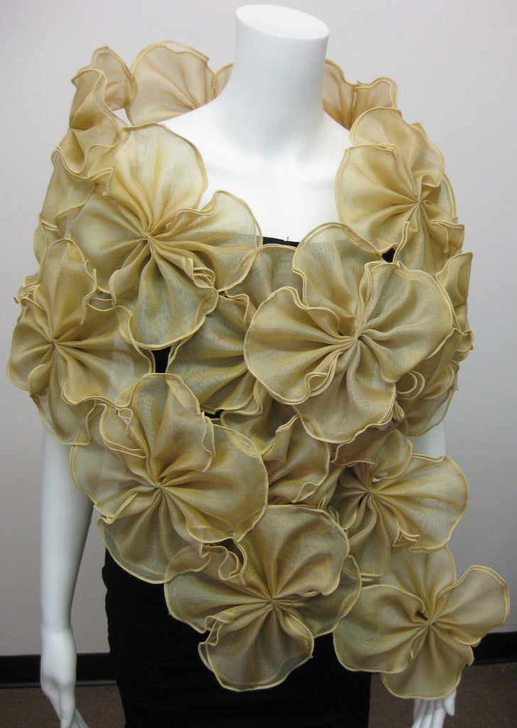 Metallic silk organza wrap made of attached gold flowers providing an opening for the arms;