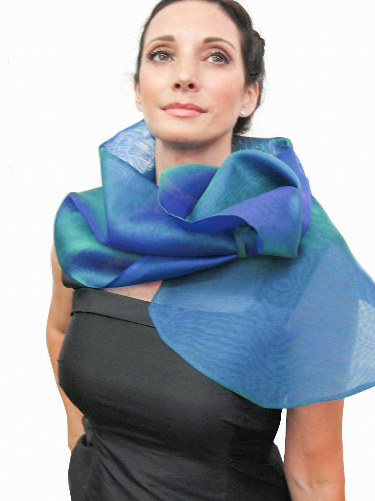 A blue silk organza wrap with a loop closure for easy adjustment and may be worn as a wrap or scarf. Simple, elegant and dramatic, it creates different looks by pulling the piece through the loop wrap around neck