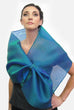 A blue silk organza wrap with a loop closure for easy adjustment and may be worn as a wrap or scarf.  Simple, elegant and dramatic, it creates different looks by pulling the piece through the loop.