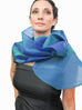 A blue silk organza wrap with a loop closure for easy adjustment and may be worn as a wrap or scarf.  Simple, elegant and dramatic, it creates different looks by pulling the piece through the loop wrap around neck